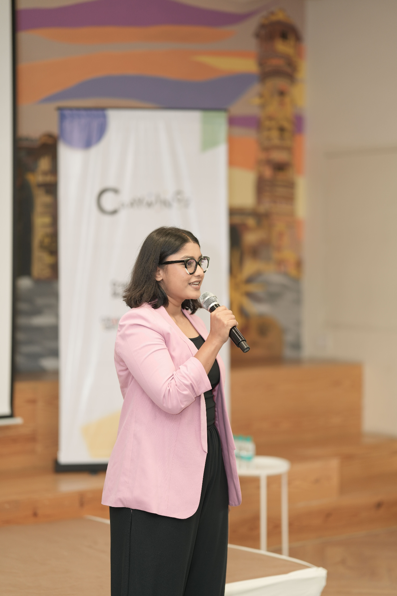 Presenter on stage in pink blazer